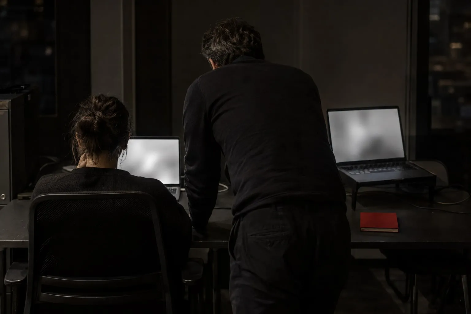 An employee at a desk and a laptop running beside them, a consultant leaning in to compare the two.